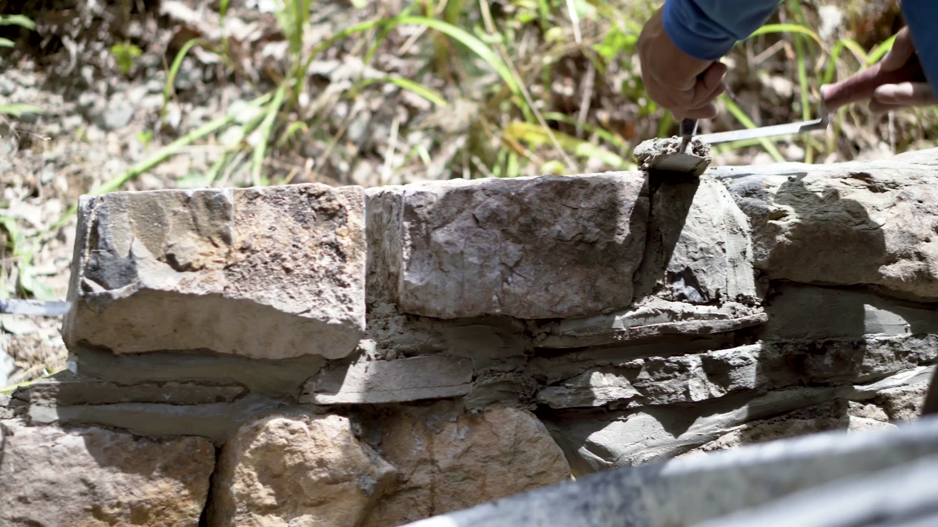 A mason laying natural stone with trowel and mortar — close-up craftsmanship
