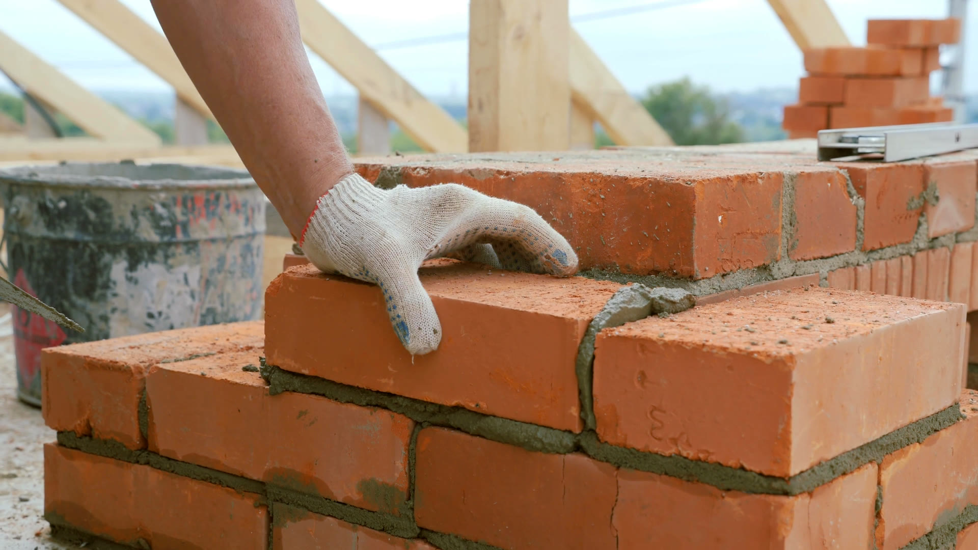 Close-up of a mason laying brick with trowel and mortar, course by course